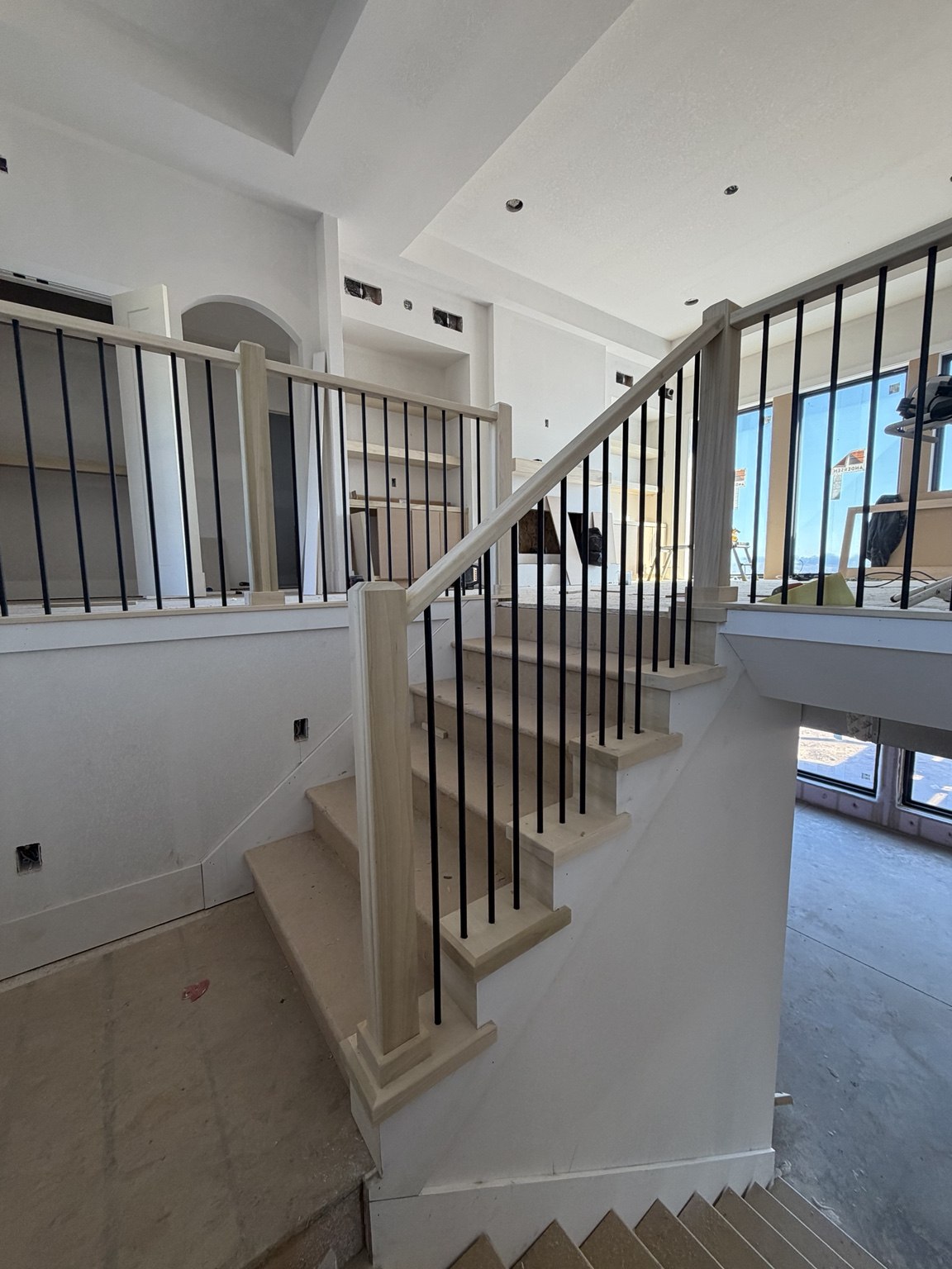Wood staircase and black metal balusters during an interior construction project